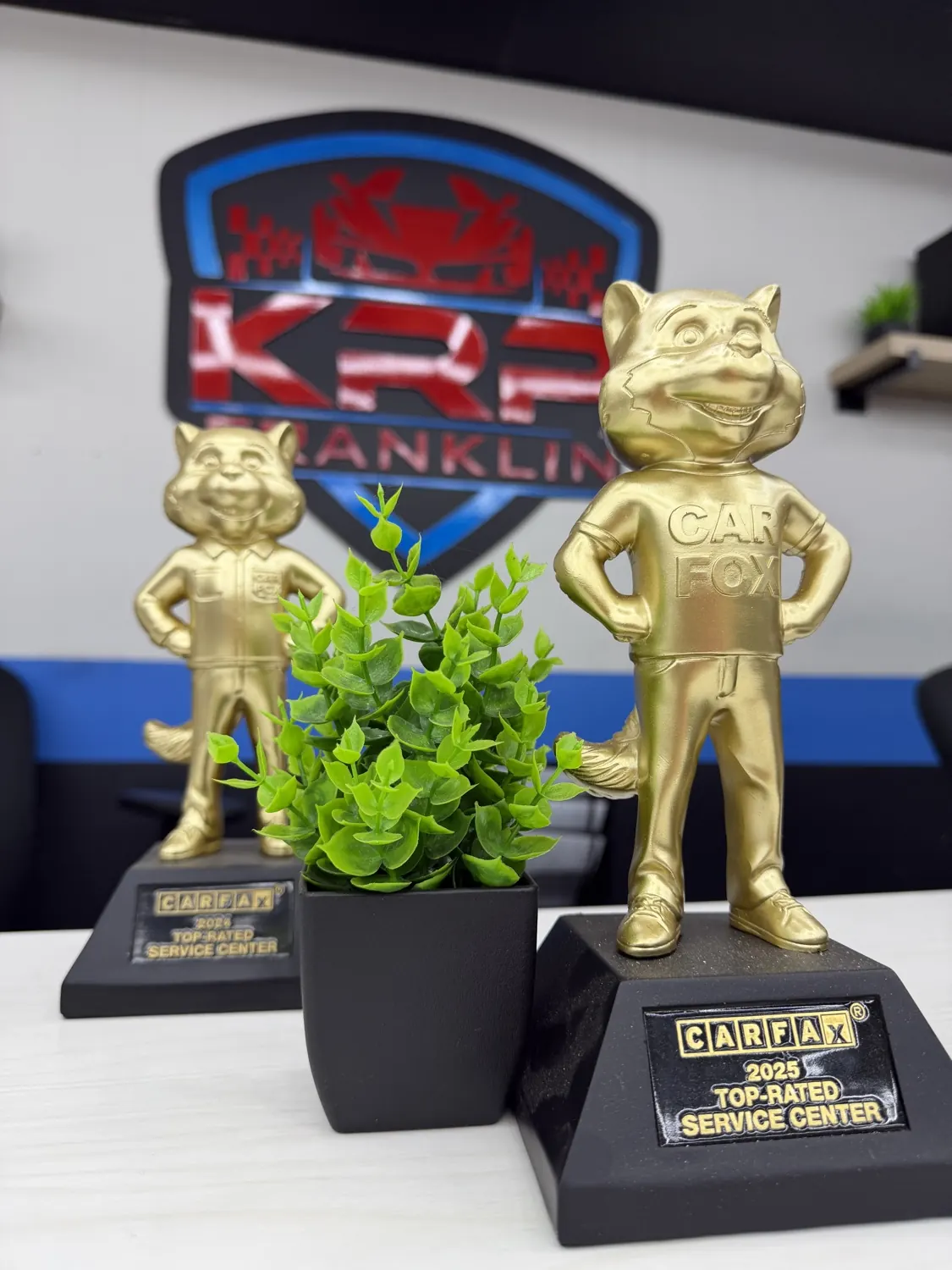 The Carfax 2024 and 2025 Top-Rated Service Center awards below the KRP Franklin sign